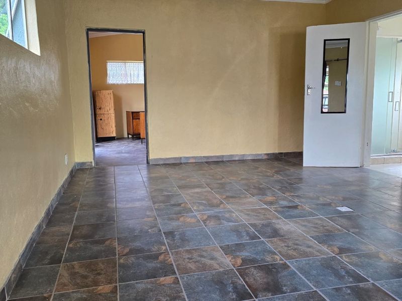 An empty living area featuring dark slate-style floor tiles and yellow-toned walls, providing a blank canvas for interior design updates.