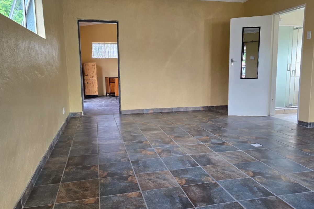 An empty living area featuring dark slate-style floor tiles and yellow-toned walls, providing a blank canvas for interior design updates.