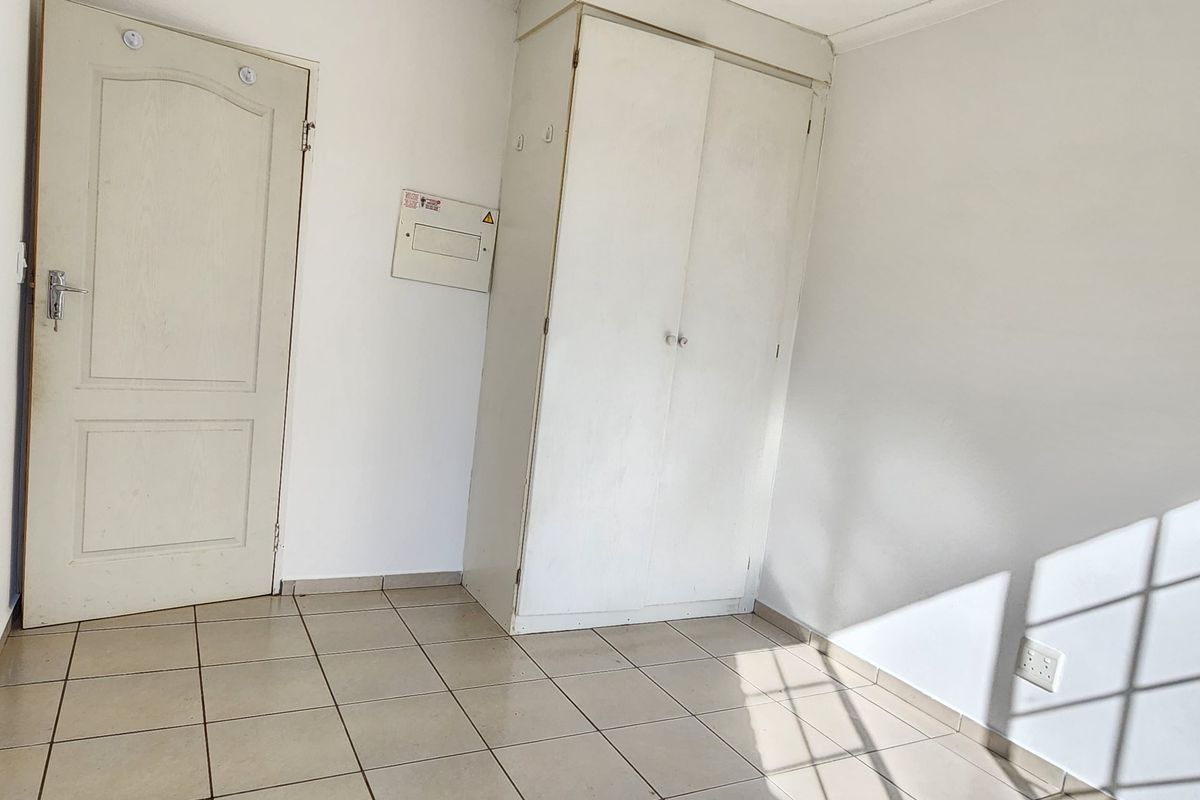 A vacant bedroom featuring tiled flooring, a built-in cupboard, and a wall-mounted electrical distribution board.