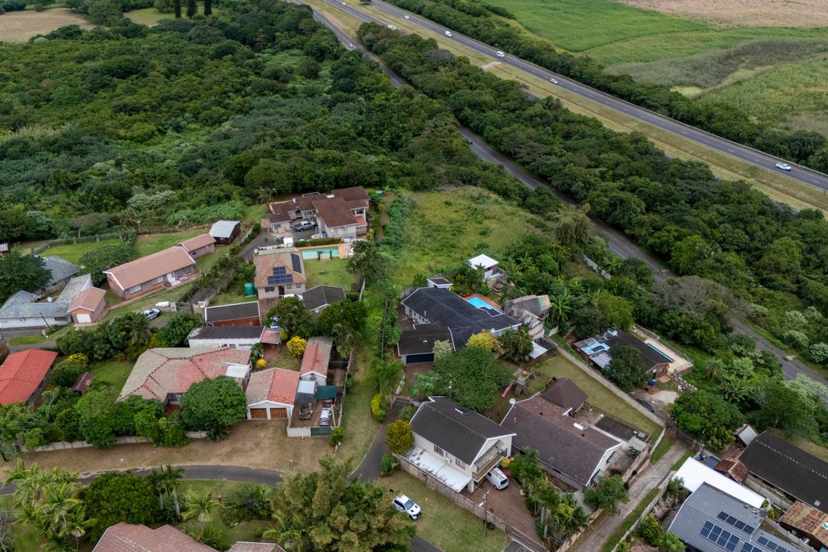 An aerial view of a residential neighborhood showing surrounding vegetation and proximity to a major highway.