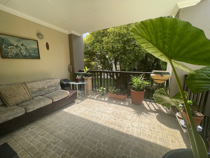 A covered balcony featuring tiled flooring and a timber balustrade, offering a pleasant outdoor space for relaxation.