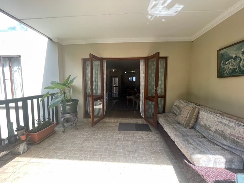 A covered patio area featuring tiled flooring and wooden double doors providing access to the interior living space.