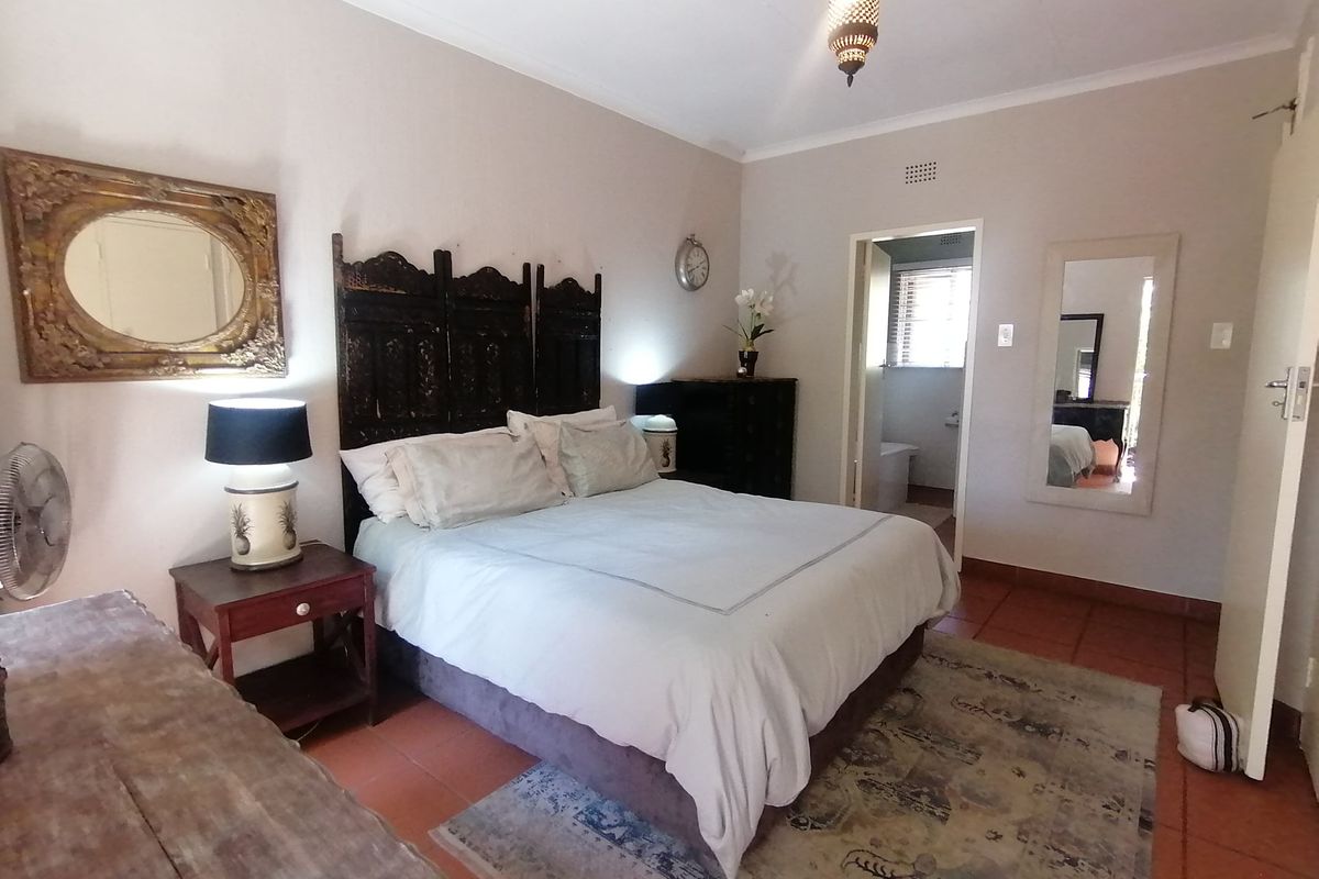 A bedroom featuring terracotta floor tiles, cove cornicing, and direct access to an en-suite bathroom.