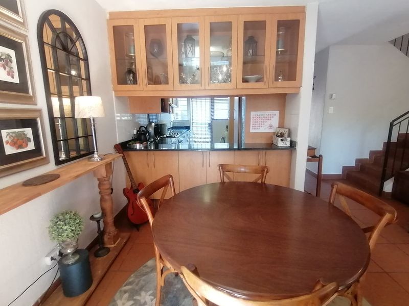 A functional kitchen area featuring built-in wooden cabinetry, glass-fronted display cupboards, and durable granite countertops, seamlessly integrated into the dining space.
