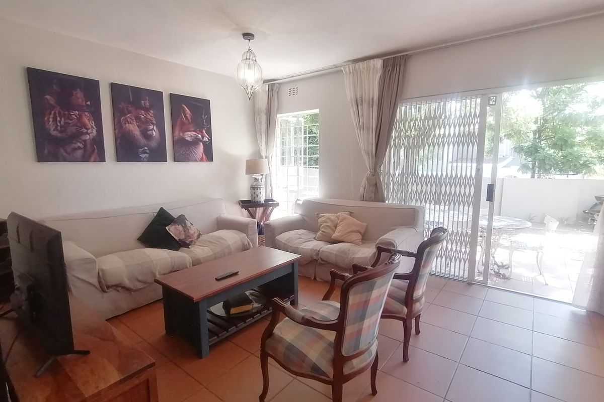 A comfortable living room featuring tiled flooring, a pendant light, and a sliding glass door with a security gate leading to the patio.