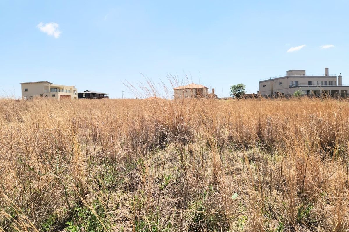 A view of a vacant residential plot featuring dry grass and surrounding neighborhood properties.