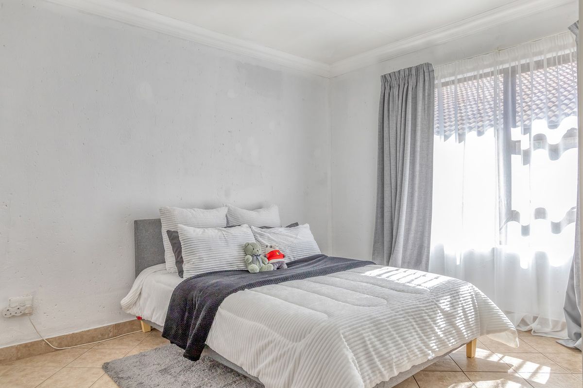 A bedroom featuring tiled flooring, coved ceilings, and natural light through a window with curtain tracks.