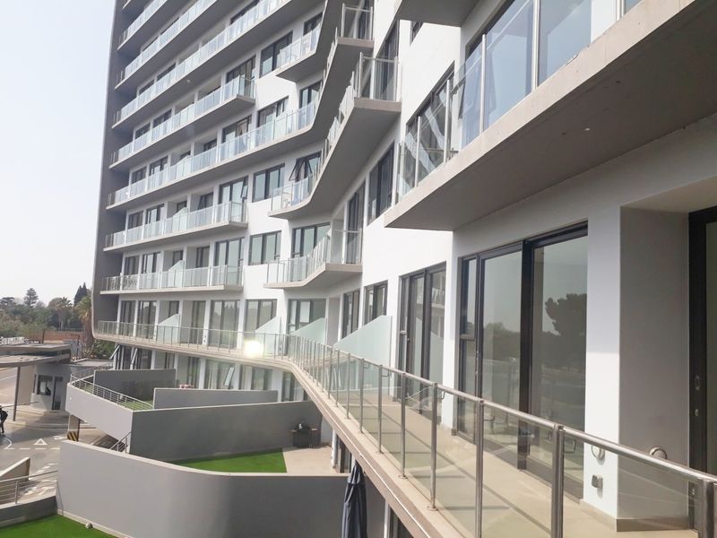 A modern multi-story apartment building exterior featuring glass balconies and large sliding doors, showcasing contemporary architectural design and clean finishes.