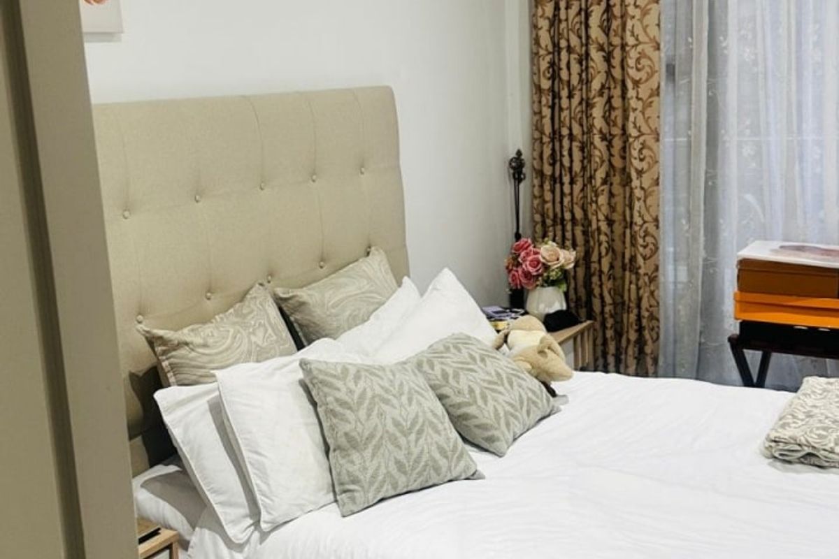 A well-maintained bedroom featuring neutral tiled flooring, recessed ceiling lighting, and floor-to-ceiling window treatments.