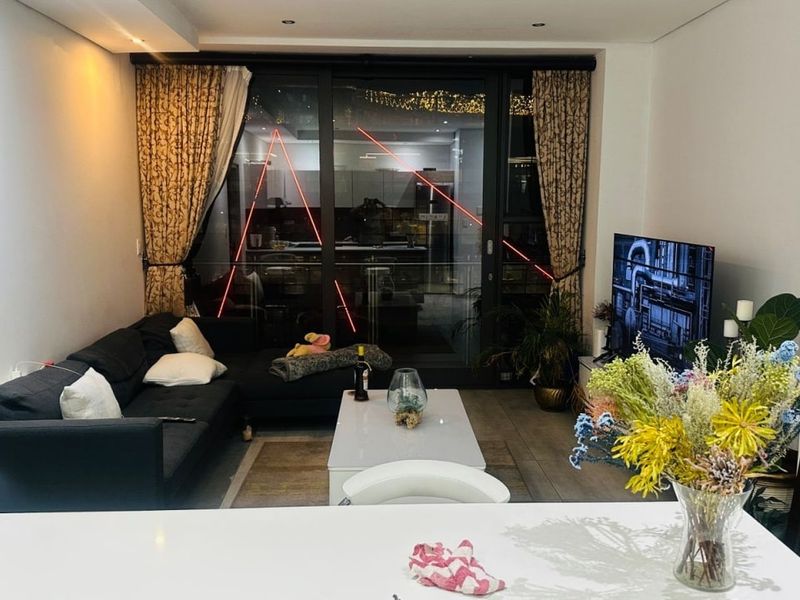 Open-plan living area featuring tiled flooring, recessed downlighting, and large sliding glass doors providing access to the balcony.