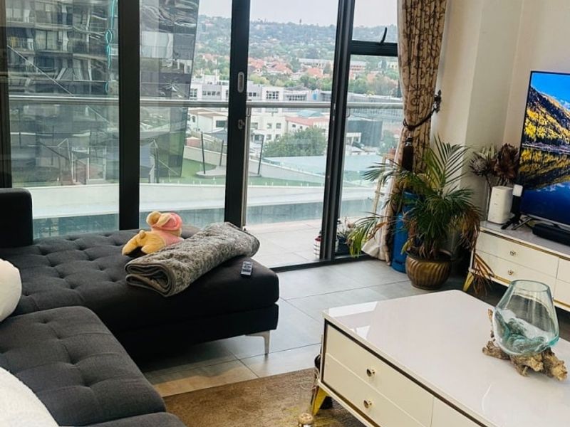 Modern living room featuring floor-to-ceiling windows with sliding doors, providing ample natural light and expansive urban views.