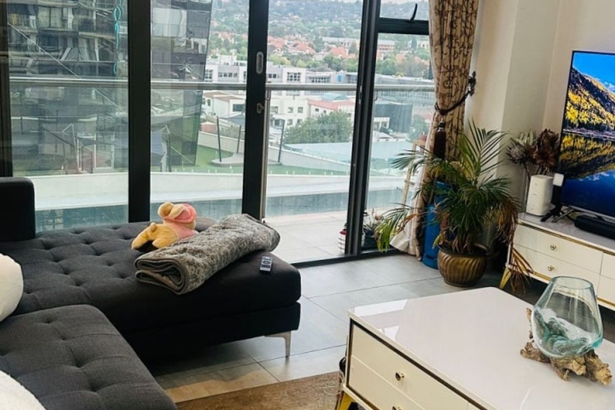Modern living room featuring floor-to-ceiling windows with sliding doors, providing ample natural light and expansive urban views.