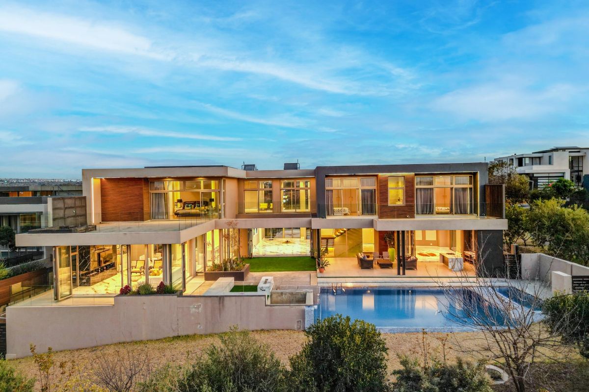 Stunning modern double-story residence featuring a large swimming pool, expansive covered patio, and seamless indoor-outdoor flow with extensive glass sliding doors.