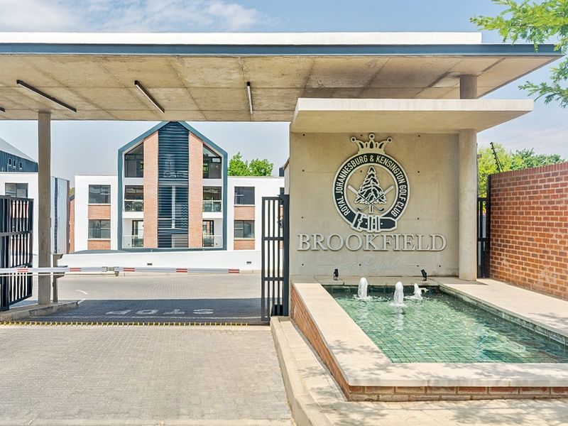 The secure entrance to Brookfield at Royal, featuring a modern concrete canopy, gated access, and a decorative water feature.