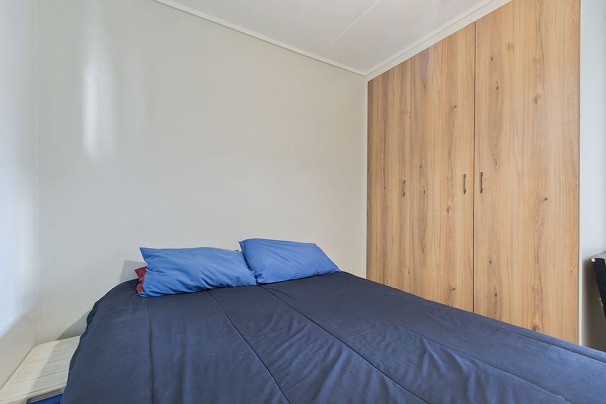 A functional bedroom featuring a built-in wooden wardrobe with ample storage space.
