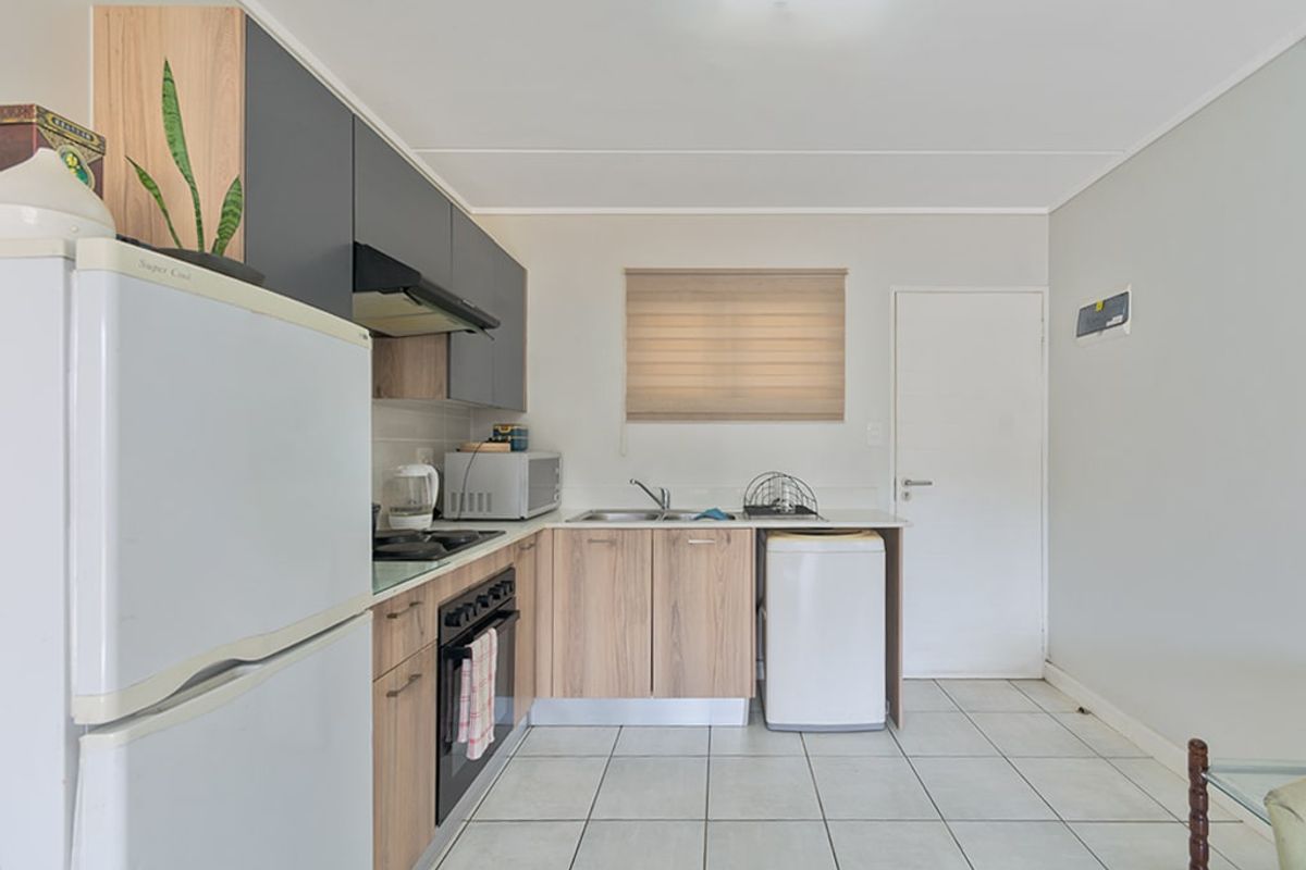 A functional kitchen featuring modern two-tone cabinetry, built-in oven and hob, tiled flooring, and a neutral color palette.