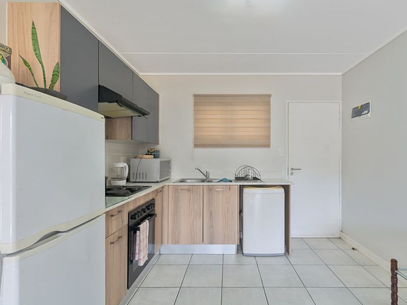 A functional kitchen featuring modern two-tone cabinetry, built-in oven and hob, tiled flooring, and a neutral color palette.