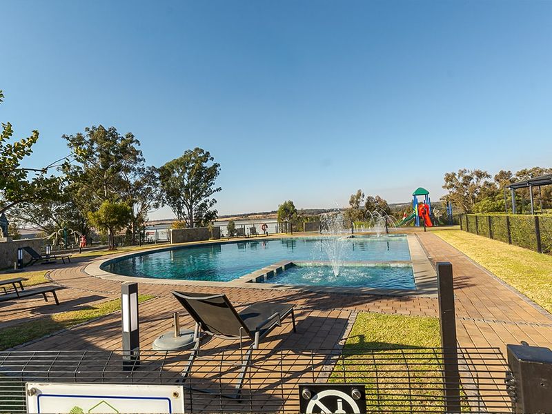 A well-maintained communal swimming pool area featuring a water fountain, paved decking, and landscaped surroundings within the apartment complex.