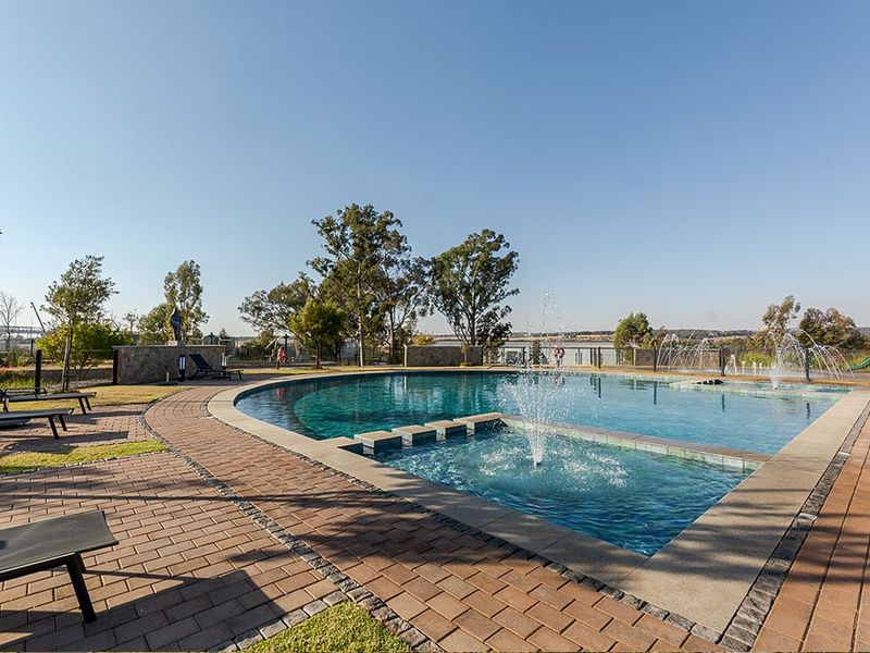 A well-maintained communal swimming pool area featuring a water fountain, paved decking, and scenic views, providing an inviting outdoor recreational space.