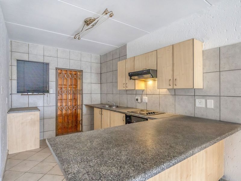 A functional kitchen featuring built-in cabinetry, laminate countertops, a built-in hob with extractor fan, and tiled backsplash, offering a practical layout for daily use.