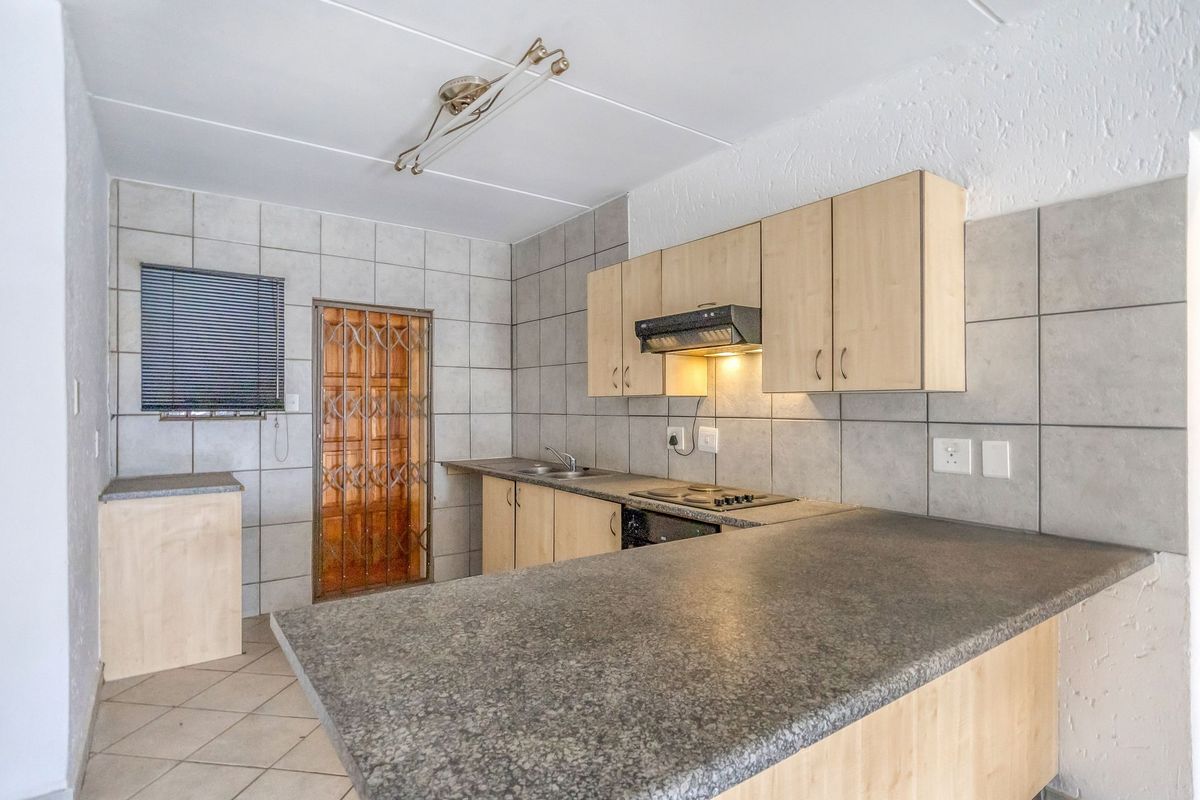 A functional kitchen featuring built-in cabinetry, laminate countertops, a built-in hob with extractor fan, and tiled backsplash, offering a practical layout for daily use.