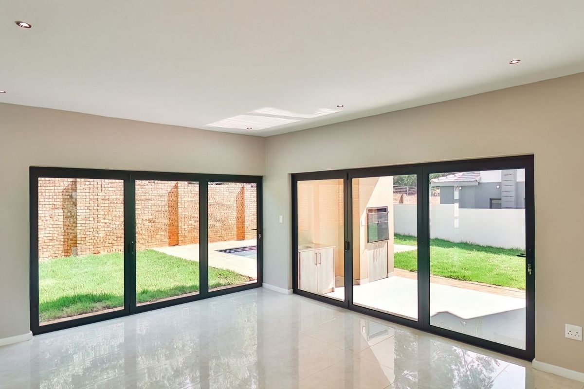 Spacious, light-filled living area featuring large aluminium stacker doors that open onto a private garden and patio with a built-in braai.