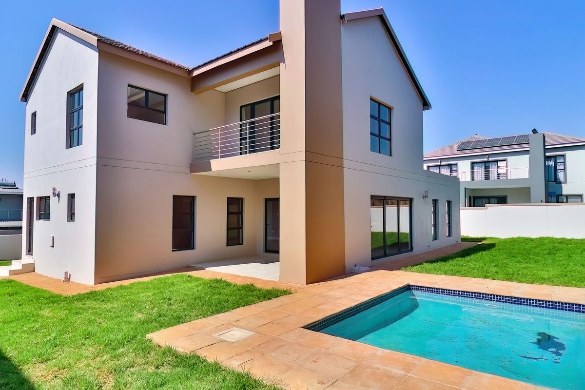 Rear view of a modern two-story house featuring a swimming pool, tiled patio area, and an upper-level balcony.