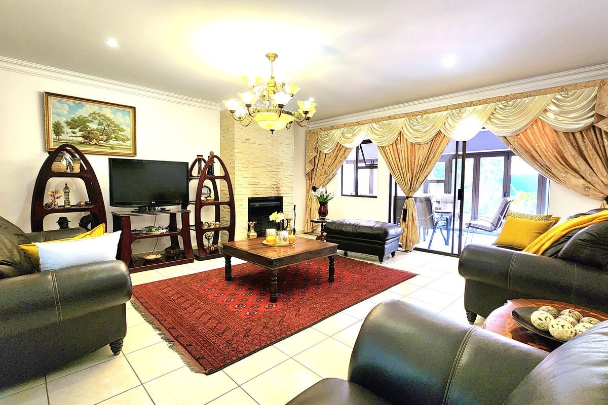 Spacious living room featuring a stone-clad fireplace, tiled flooring, and large sliding glass doors providing access to the patio area.