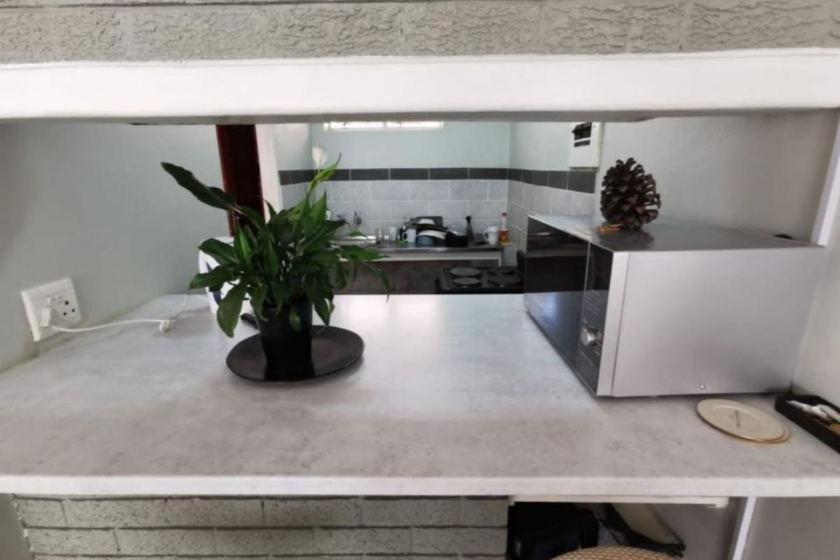 A functional kitchen area featuring a breakfast bar with a laminate countertop, tiled backsplash, and built-in cooking facilities.