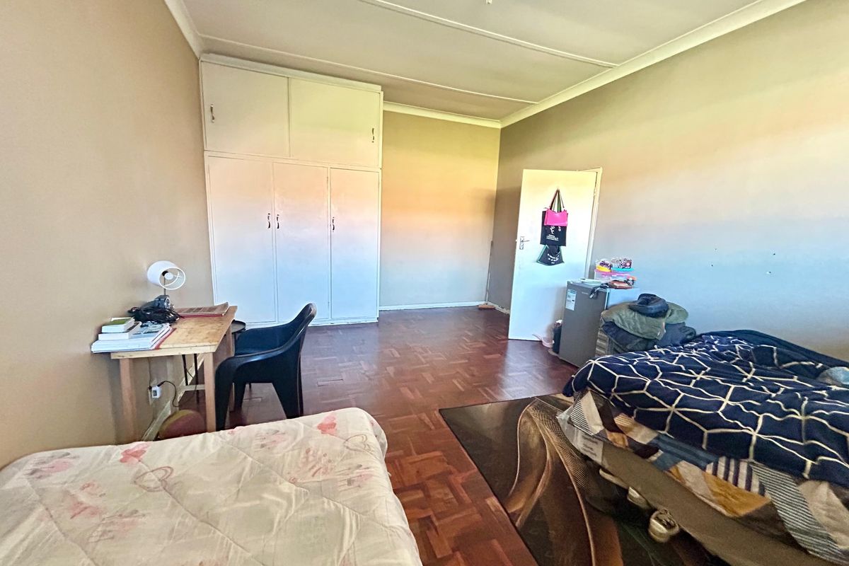 A spacious bedroom featuring classic parquet flooring and ample built-in cupboard storage, offering a functional layout ready for modern updates.