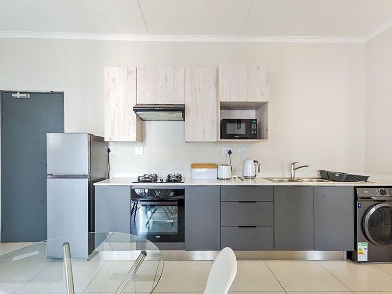 Modern kitchen featuring two-tone cabinetry, built-in oven, gas hob, extractor fan, integrated microwave, and tiled flooring.