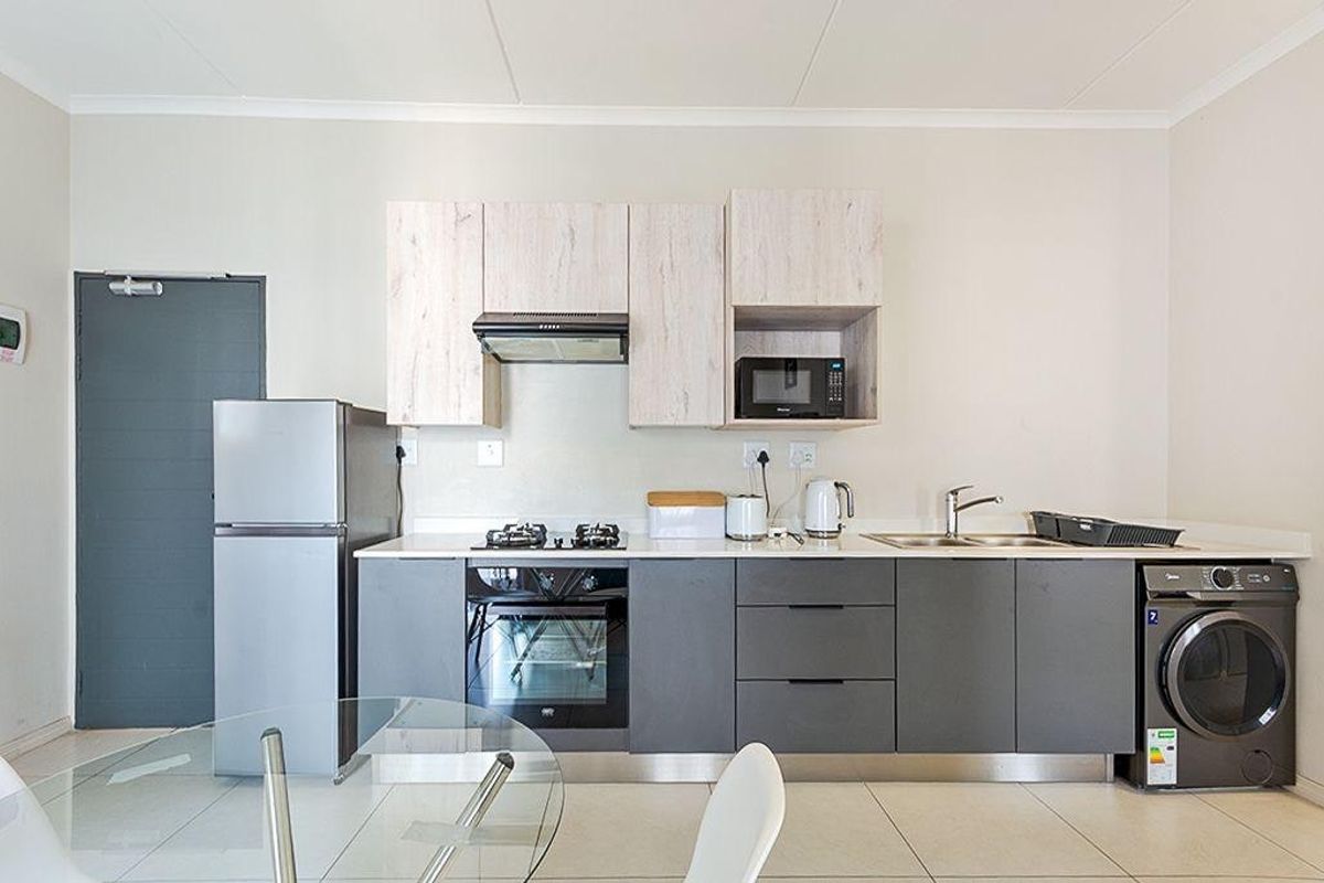 Modern kitchen featuring two-tone cabinetry, built-in oven, gas hob, extractor fan, integrated microwave, and tiled flooring.