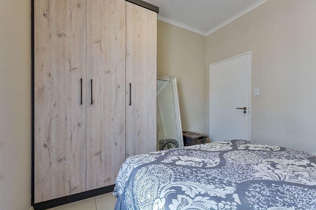 A well-maintained bedroom featuring a modern wood-grain built-in wardrobe and neutral wall finishes.