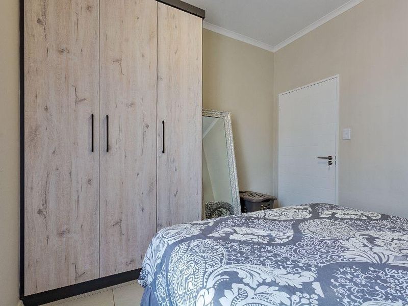 A well-maintained bedroom featuring a modern wood-grain built-in wardrobe and neutral wall finishes.