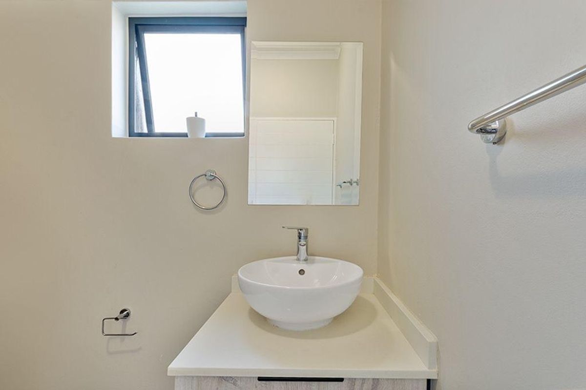 A clean and modern bathroom featuring a white vessel sink set on a vanity cabinet, complemented by a wall-mounted mirror and chrome fixtures.