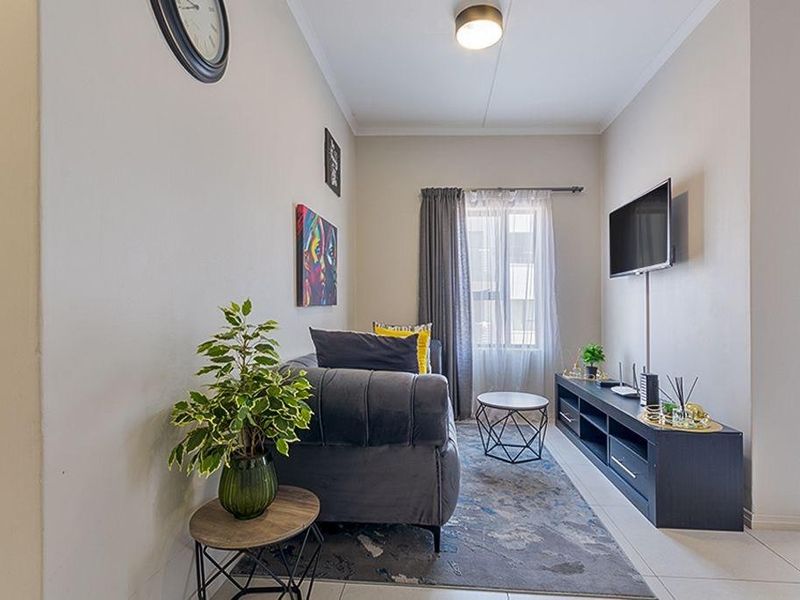 A compact living room featuring tiled flooring and neutral wall finishes, providing a functional and well-lit space.