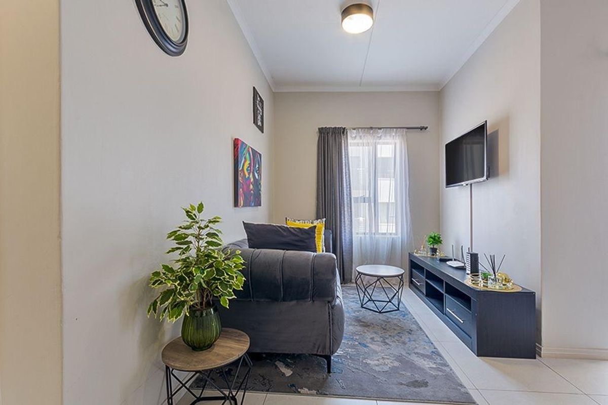 A compact living room featuring tiled flooring and neutral wall finishes, providing a functional and well-lit space.