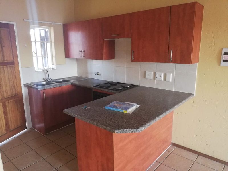 Functional kitchen featuring laminate cabinetry, a built-in electric hob, double bowl sink, and tiled splashback with a breakfast counter.