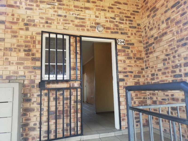 Front entrance of apartment 124 featuring a face brick facade, security gate, and external lighting.
