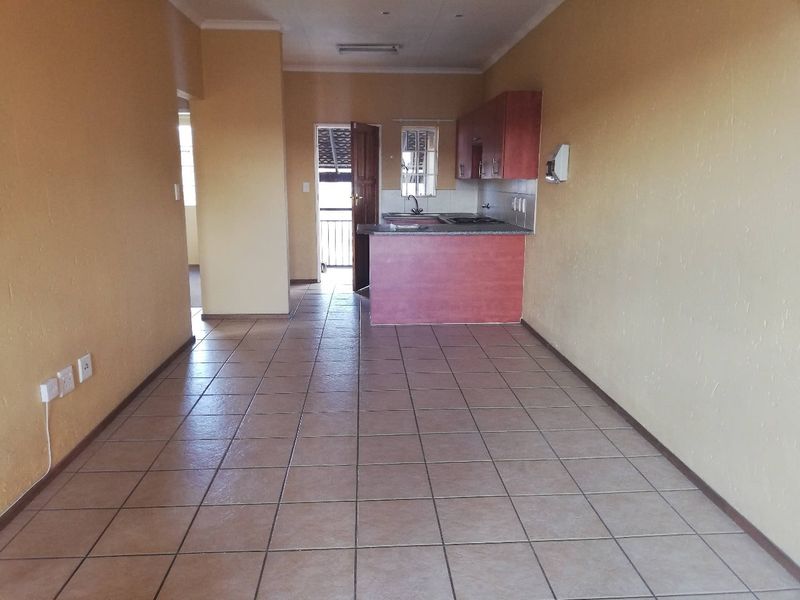 An open-plan living and kitchen area featuring tiled flooring, built-in cabinetry, and direct access to an outdoor balcony space.