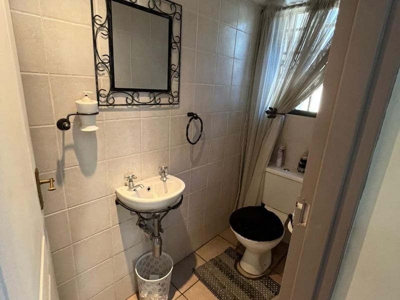 A compact guest bathroom featuring a wall-mounted basin, toilet, and neutral ceramic tiling throughout.