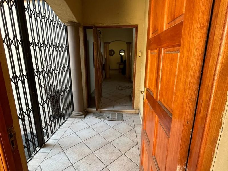 An entrance foyer featuring tiled flooring, a security gate, and an arched entryway leading into the home interior.