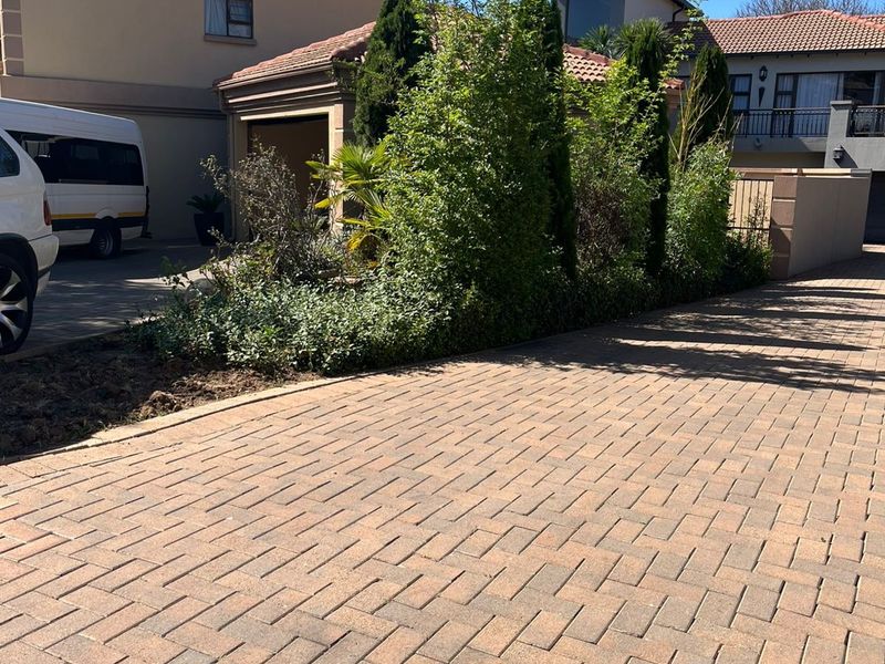 Front exterior view of the property featuring a paved driveway, well-maintained landscaping, and a multi-level structure with a tiled roof.