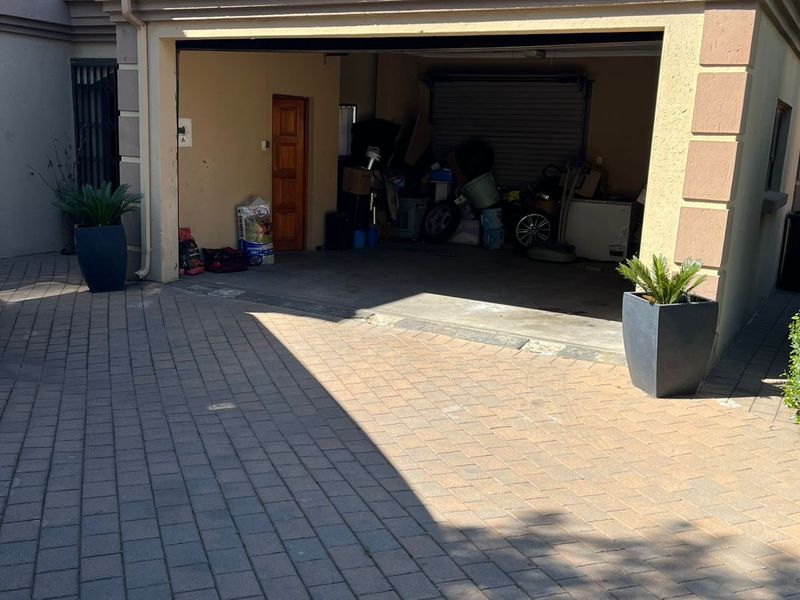 A view of a residential garage with a paved driveway and tiled roof structure.