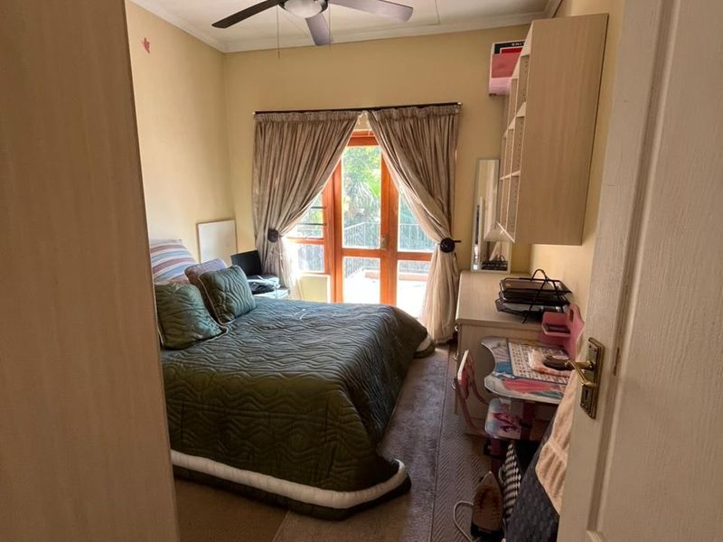 A bedroom featuring a ceiling fan, built-in wall shelving, and a sliding glass door providing access to an outdoor area.