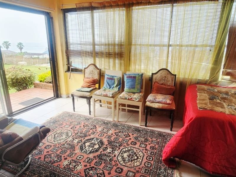 A sunlit living area featuring large windows with blinds, tiled flooring, and direct access to an outdoor patio through a sliding glass door.