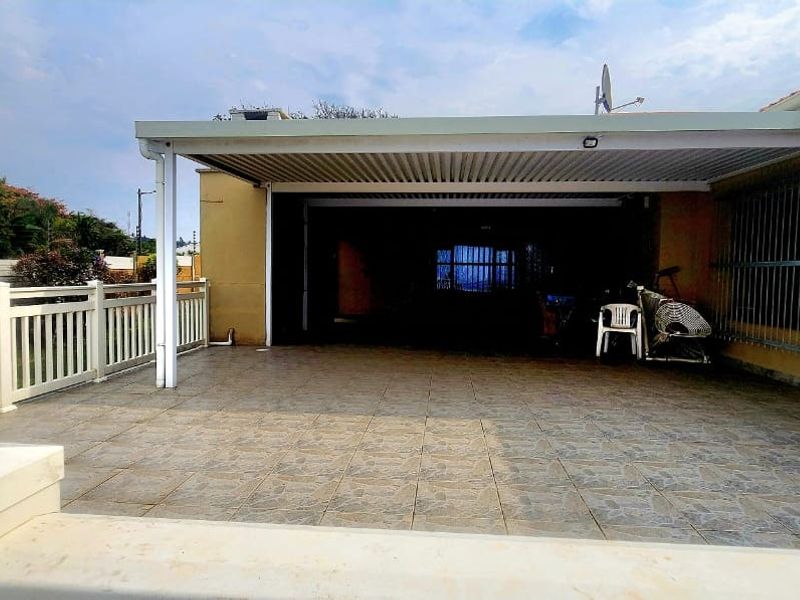 A spacious covered patio area featuring tiled flooring and security bars, providing a functional outdoor space for relaxation or entertainment.