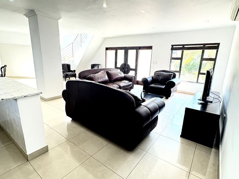 Spacious open-plan living area featuring tiled floors, a kitchen island, and direct access to the outdoors via sliding doors.