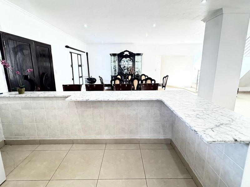 Open-plan living area featuring a marble-look breakfast bar, tiled flooring, and recessed lighting, seamlessly connecting the kitchen and dining space.