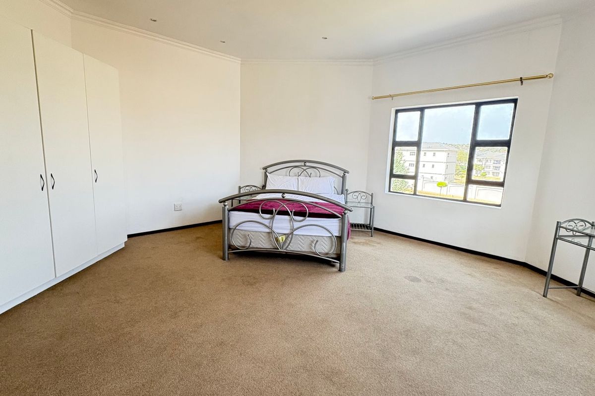 Spacious bedroom featuring built-in cupboards, carpeted flooring, and large windows providing natural light.